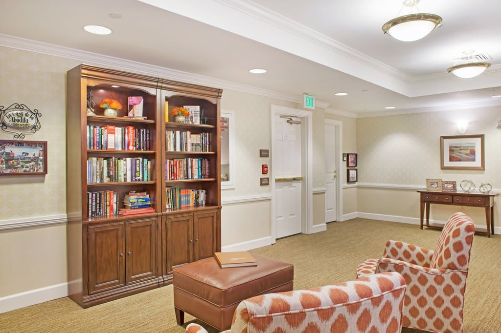A cozy lounge area with a bookshelf filled with books and comfortable seating.