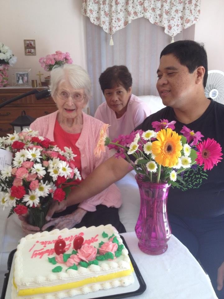 Three people celebrating with flowers and a cake.