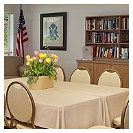 A library meeting room with a table and chairs, decorated with flowers and an American flag.