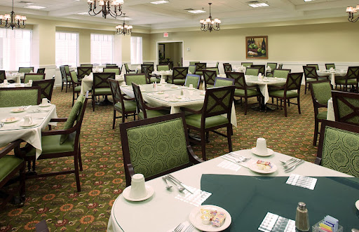A spacious dining room set up with tables and chairs, featuring green decor and a formal atmosphere.
