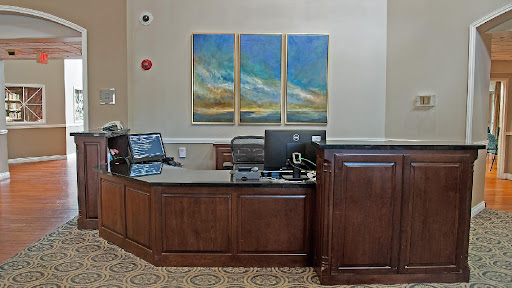 A modern reception area featuring a wooden desk, computers, and abstract artwork on the wall.