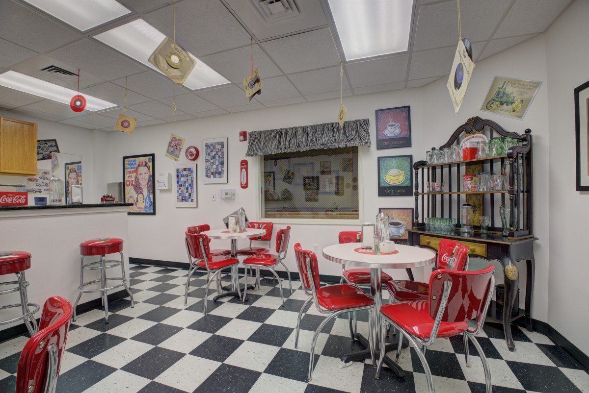 A retro 50s-style diner with red chairs and a checkerboard floor.