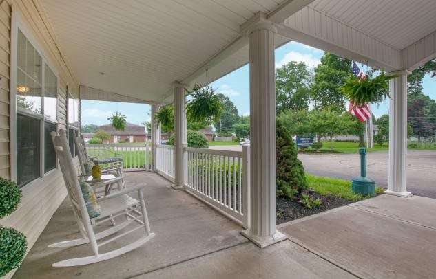 A cozy porch with rocking chairs and hanging plants overlooking a suburban street.