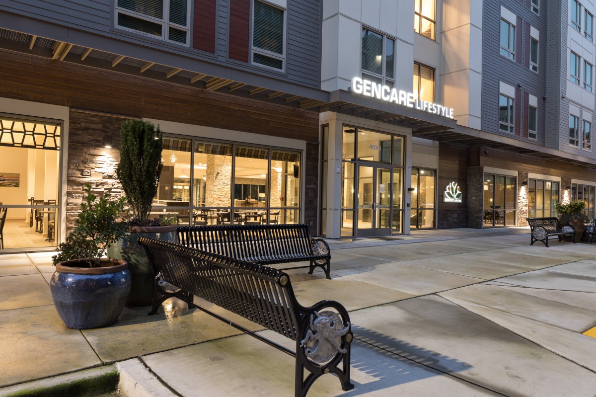 Entrance to a commercial building at night with a bench in front.