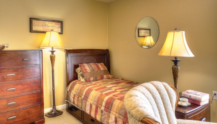 A cozy bedroom with a single bed, armchair, and warm lighting.