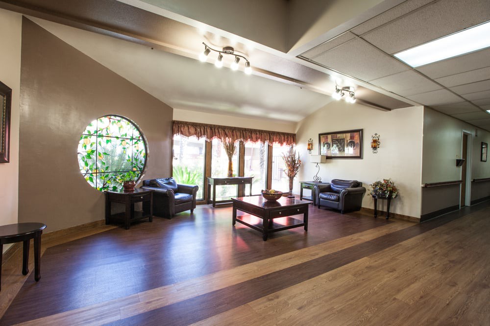 A spacious living room with wooden flooring and ample natural light streaming through large windows.