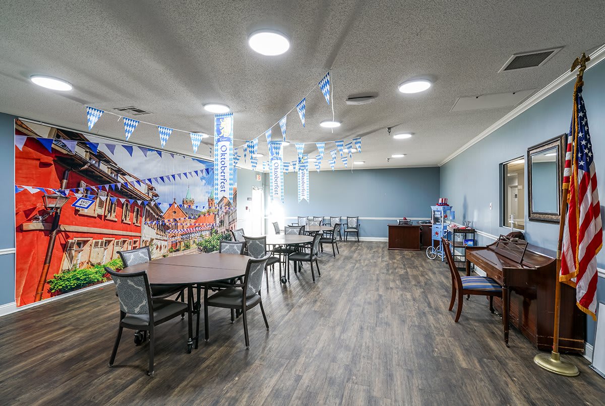 A well-lit dining area with tables and chairs, decorated with banners and lights.