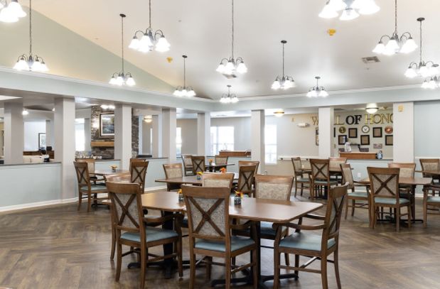 A spacious dining area with wooden tables and chairs, well-lit by hanging lights.