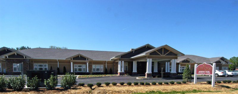 A modern, single-story building with a spacious entrance and landscaped surroundings.