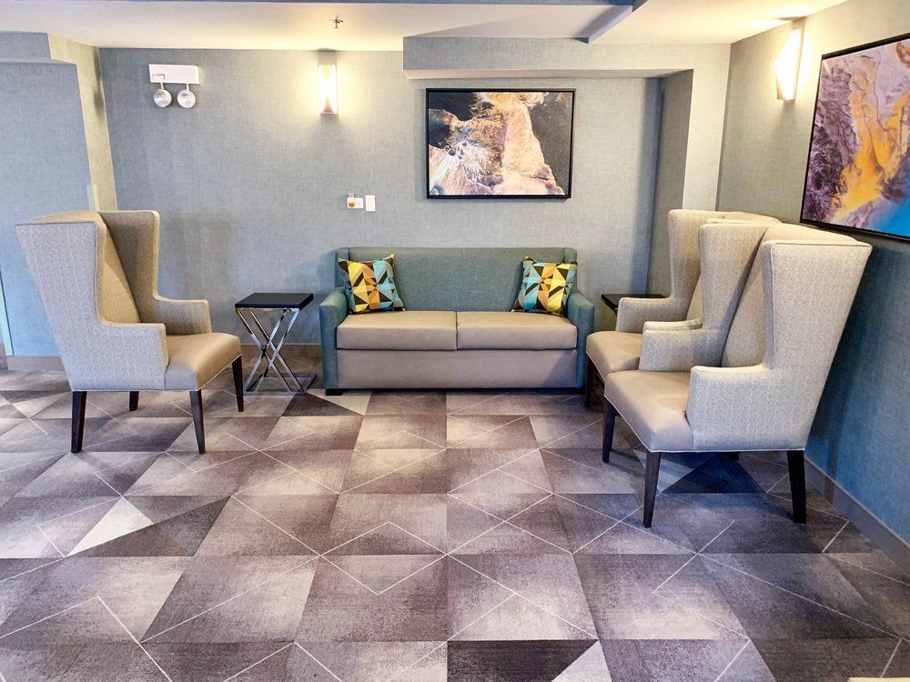 A modern lobby area featuring armchairs, a sofa, and a painting on the wall.