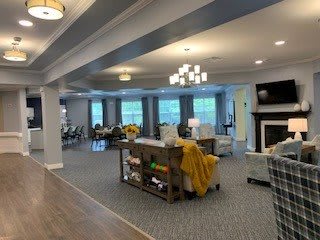 A spacious and elegantly decorated living area featuring comfortable seating, a fireplace, and ample natural light from large windows.