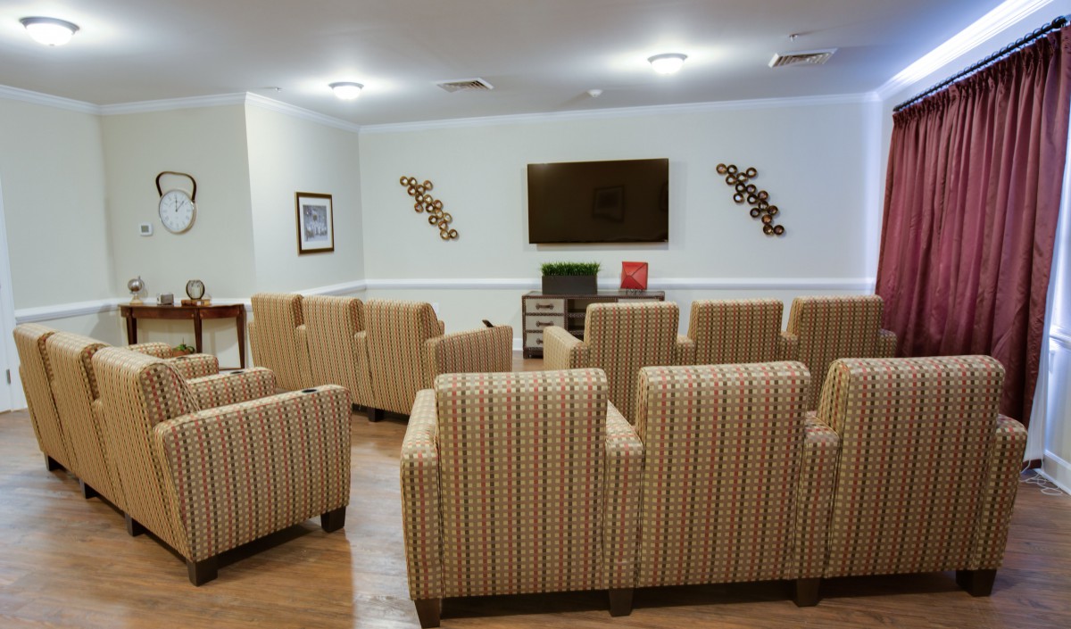 A cozy seating area with multiple chairs arranged in front of a wall-mounted television.