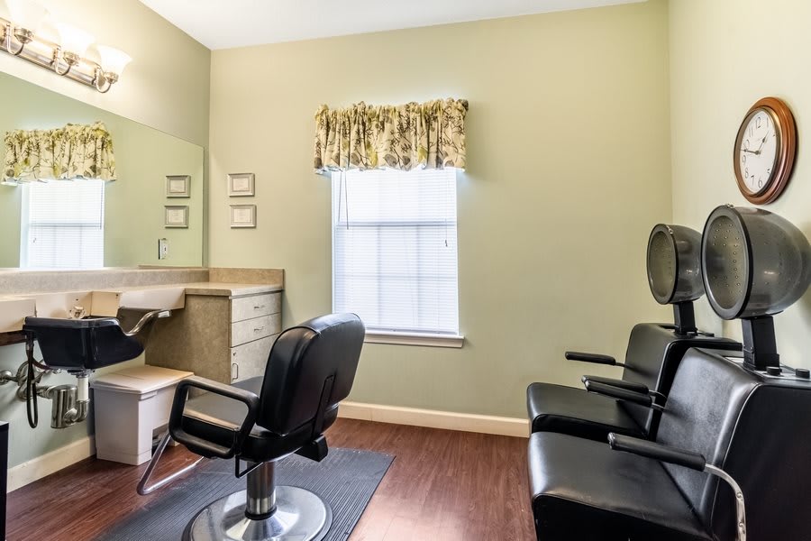 Interior of a hair salon with chairs and a mirror.