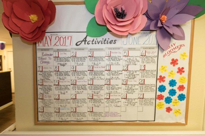 A decorated activities calendar for May 2017 with colorful paper flowers.