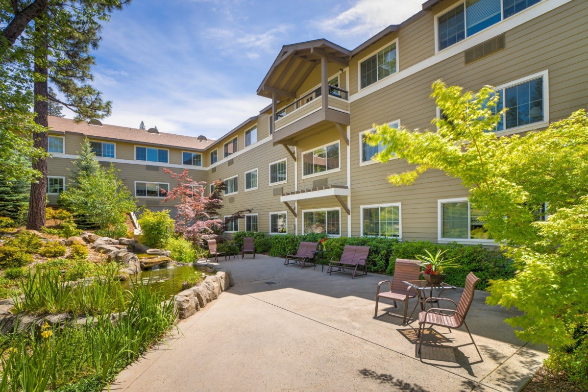 A serene courtyard in a residential apartment complex with lush landscaping and outdoor seating.