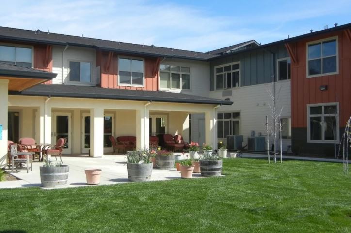 A modern two-story house with a spacious backyard and patio area.