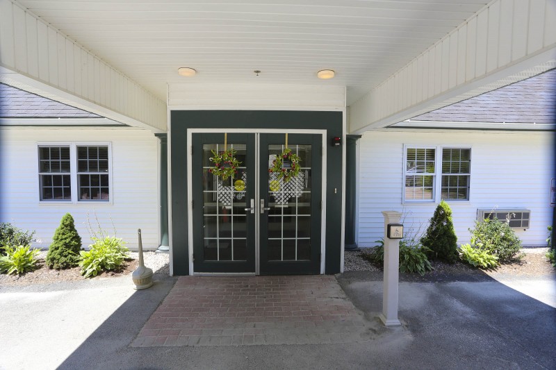 A building entrance with double green doors adorned with wreaths.