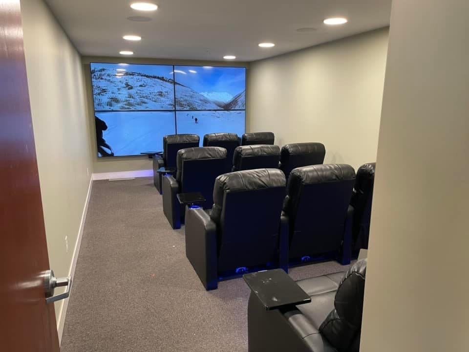 A cozy home theater setup with rows of comfortable cinema chairs facing a large screen.