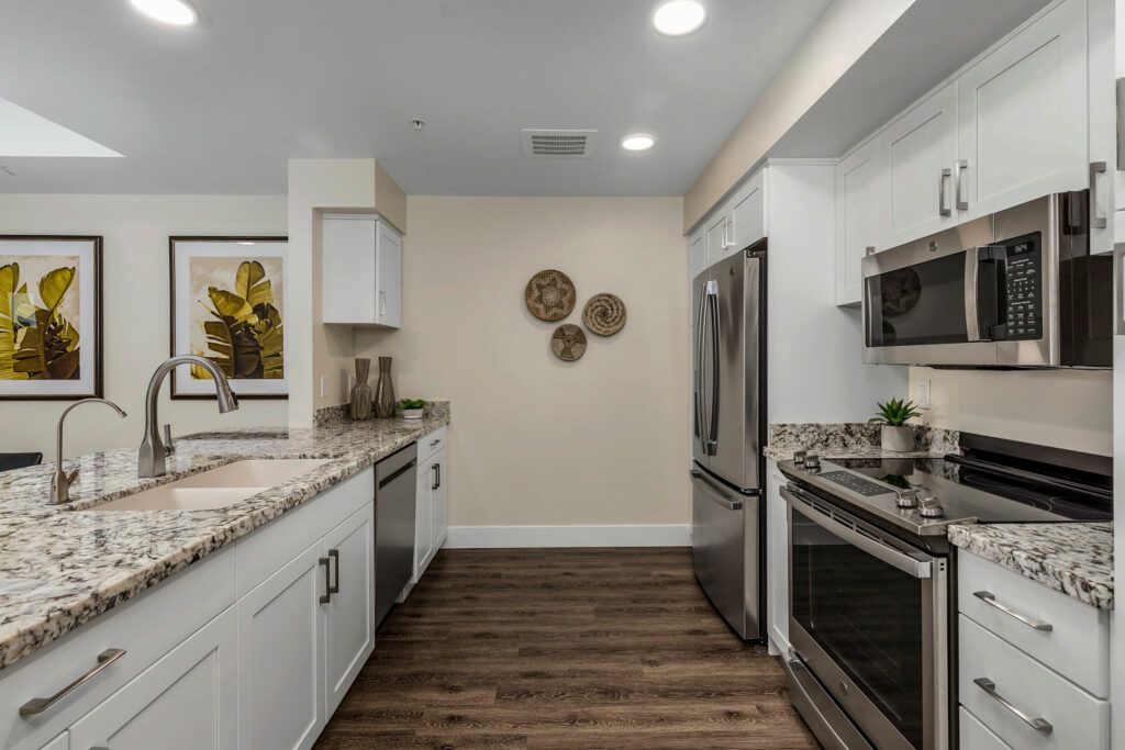 A modern kitchen with stainless steel appliances and wooden flooring.