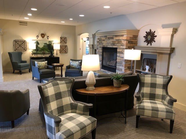 A cozy living room with comfortable seating, lamps, and a fireplace.