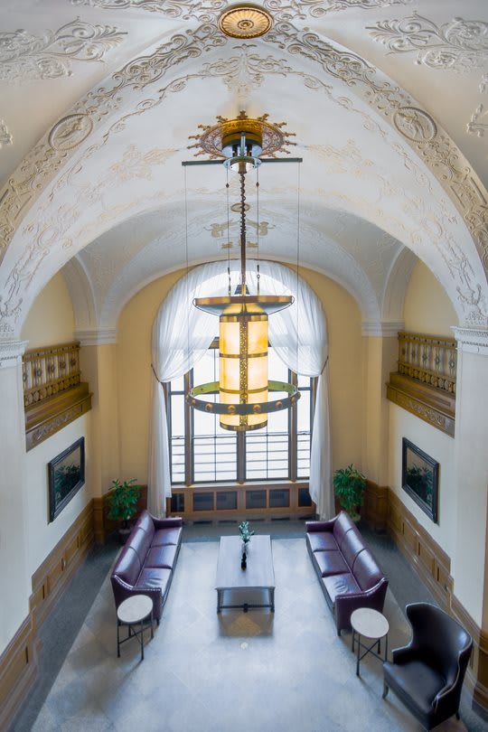 A beautifully designed interior space featuring a large chandelier, arched ceiling, and elegant seating area by a window.