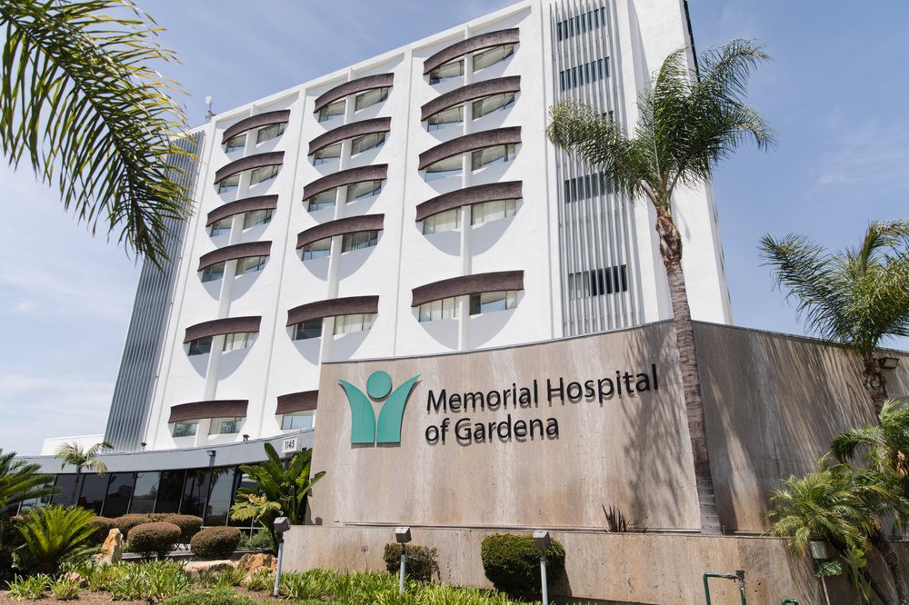 Exterior view of Memorial Hospital of Gardena with palm trees and signage.