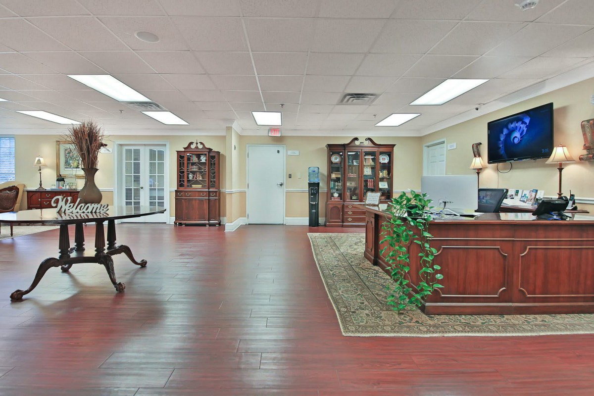 A spacious reception area with wooden furniture and decorative plants.