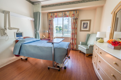 A well-lit and welcoming hospital patient room with a bed and seating area.