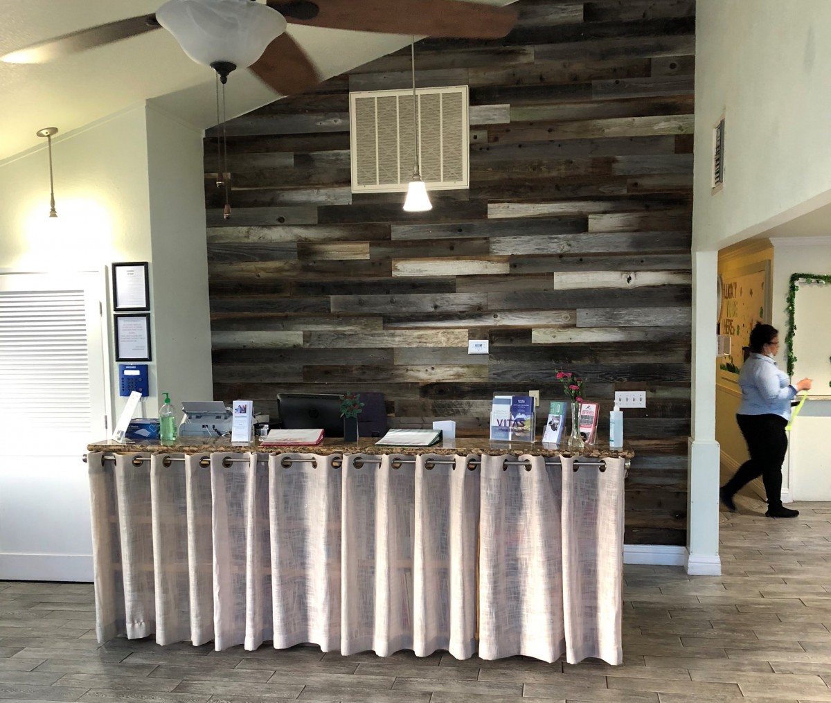 A modern reception desk with a wooden accent wall in the background.