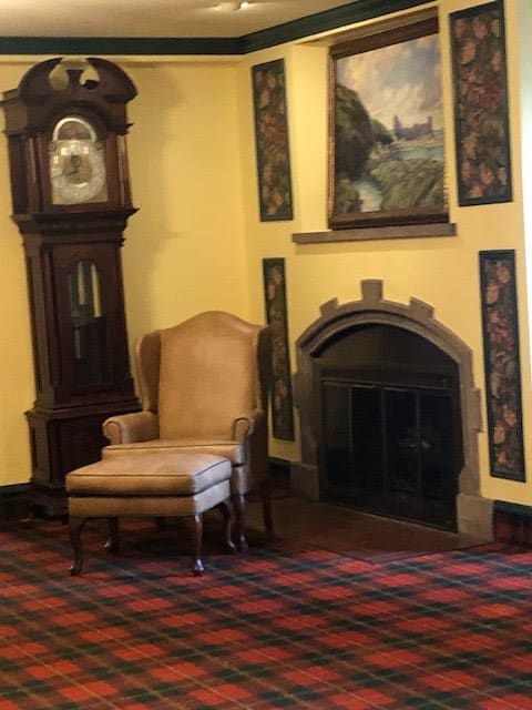 A cozy corner featuring a grandfather clock, an armchair, and a decorative fireplace in a traditionally styled room.