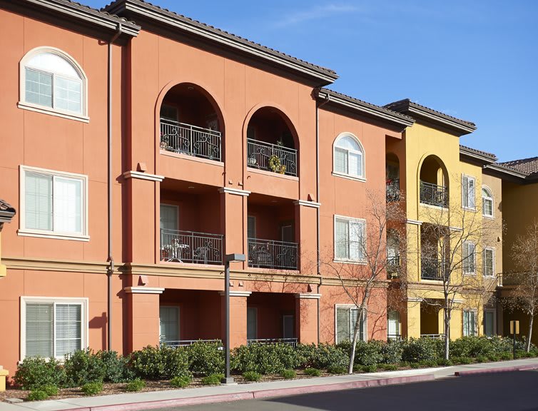 A residential apartment building with multiple balconies on a sunny day.