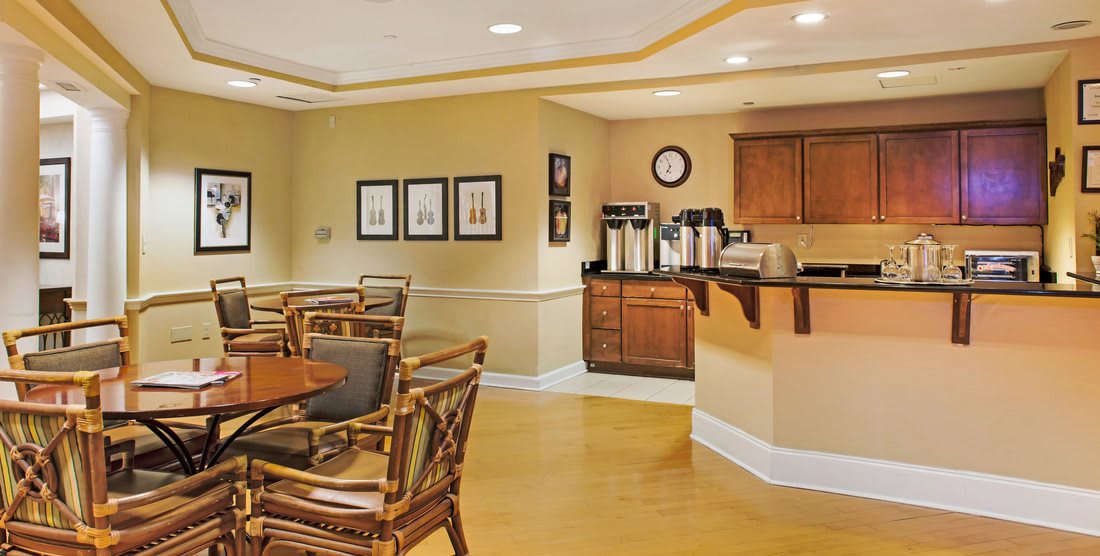A cozy dining area with a coffee station, featuring wooden tables and chairs.