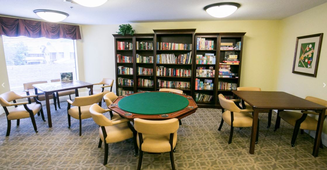 A cozy library room with a round table and bookshelves filled with books.