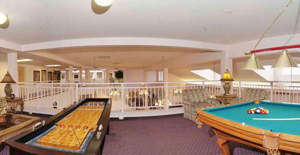 A spacious games room with a pool table and foosball table on a carpeted floor.