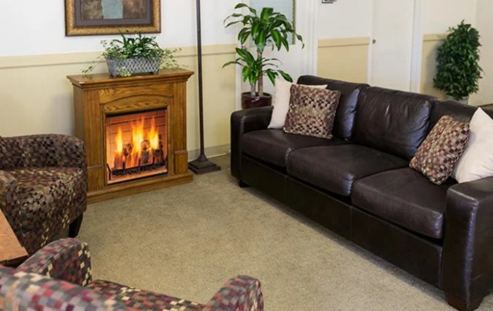 A cozy living room with a leather sofa and a warm fireplace.