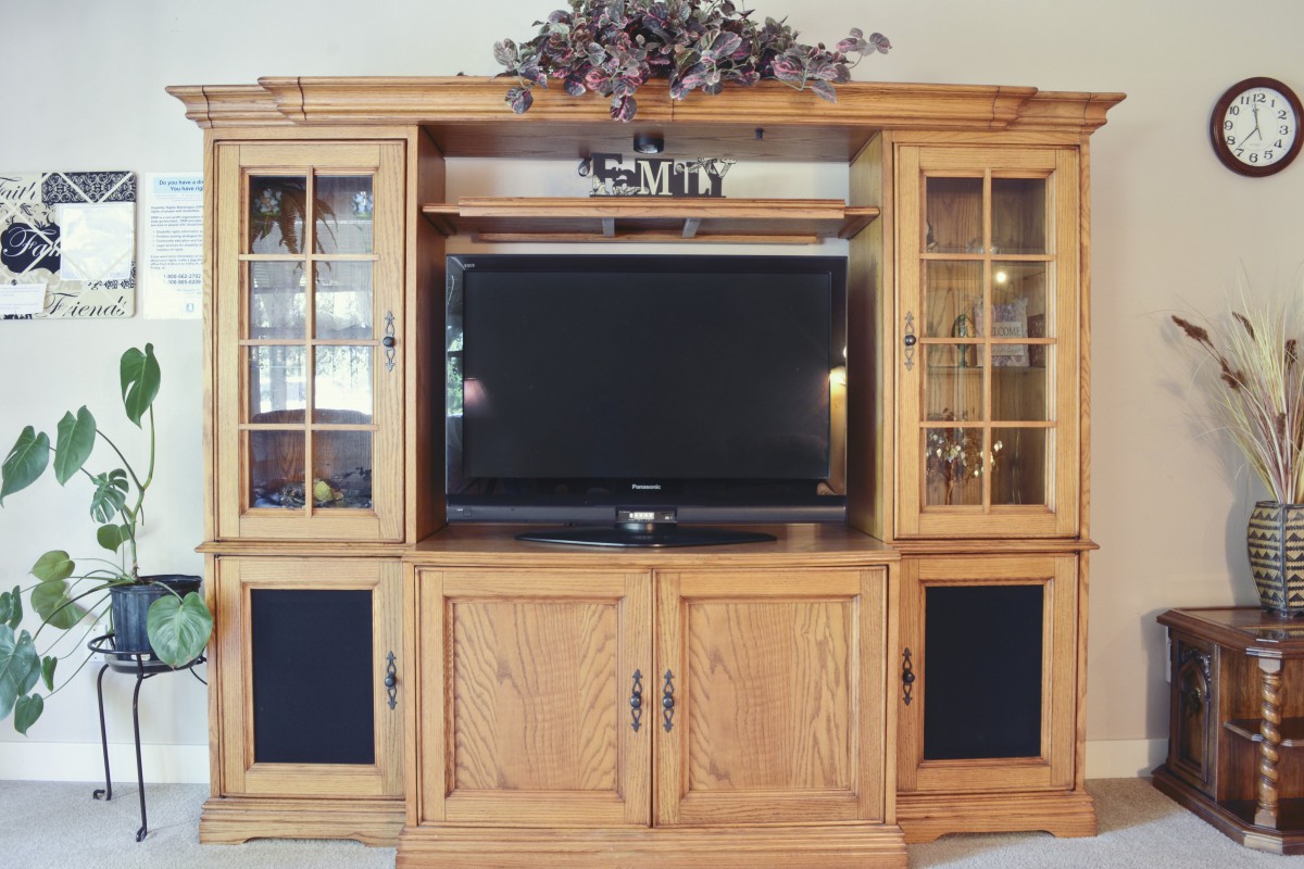 A wooden entertainment center with a TV and glass cabinets.