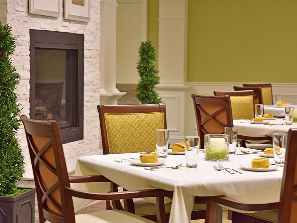 A cozy dining area with neatly set tables and a fireplace.