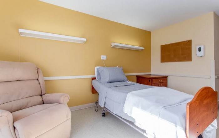 A clean and orderly hospital room featuring a single bed and chair.