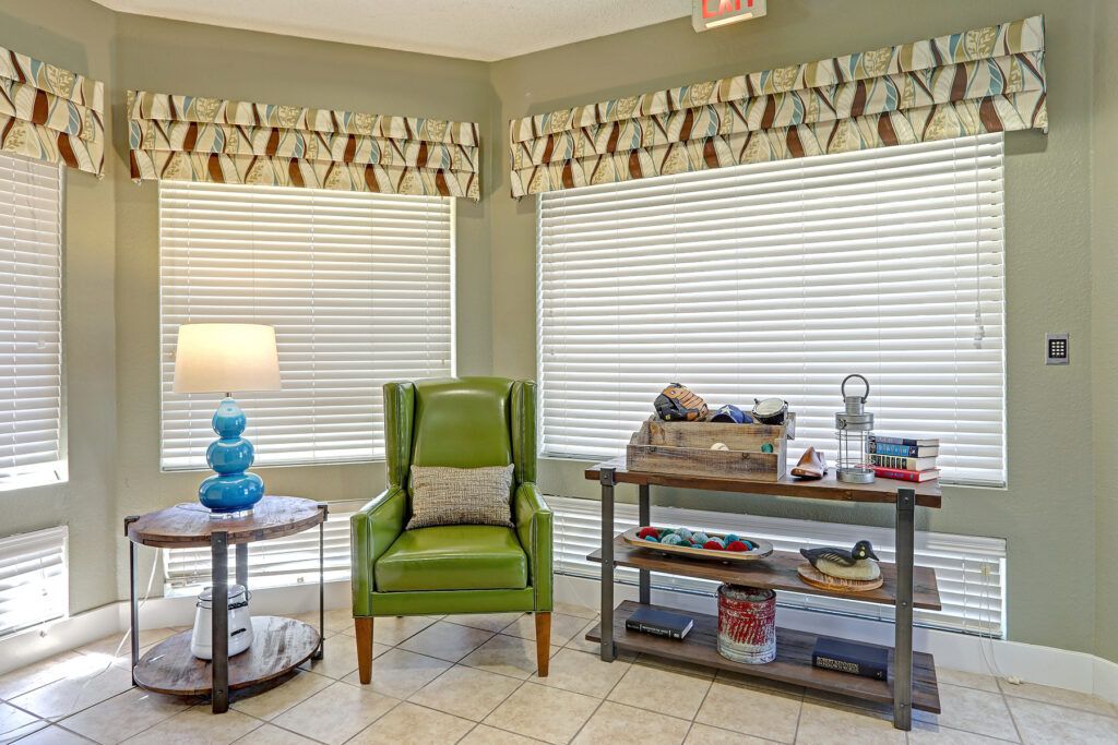 A cozy living room corner with a green armchair, decorative lamp, and stylish bookshelf.