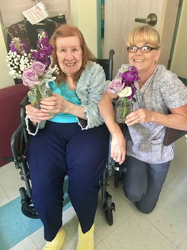 A joyful moment shared between a resident and a caregiver, both holding lovely bouquets of flowers.