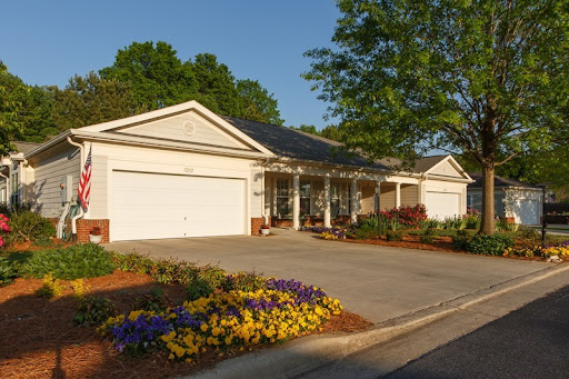 A well-maintained home with a spacious driveway, surrounded by vibrant flowers and lush greenery.