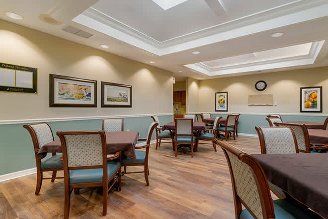 A modern dining area with neatly arranged tables and chairs, soft lighting, and artwork on the walls.