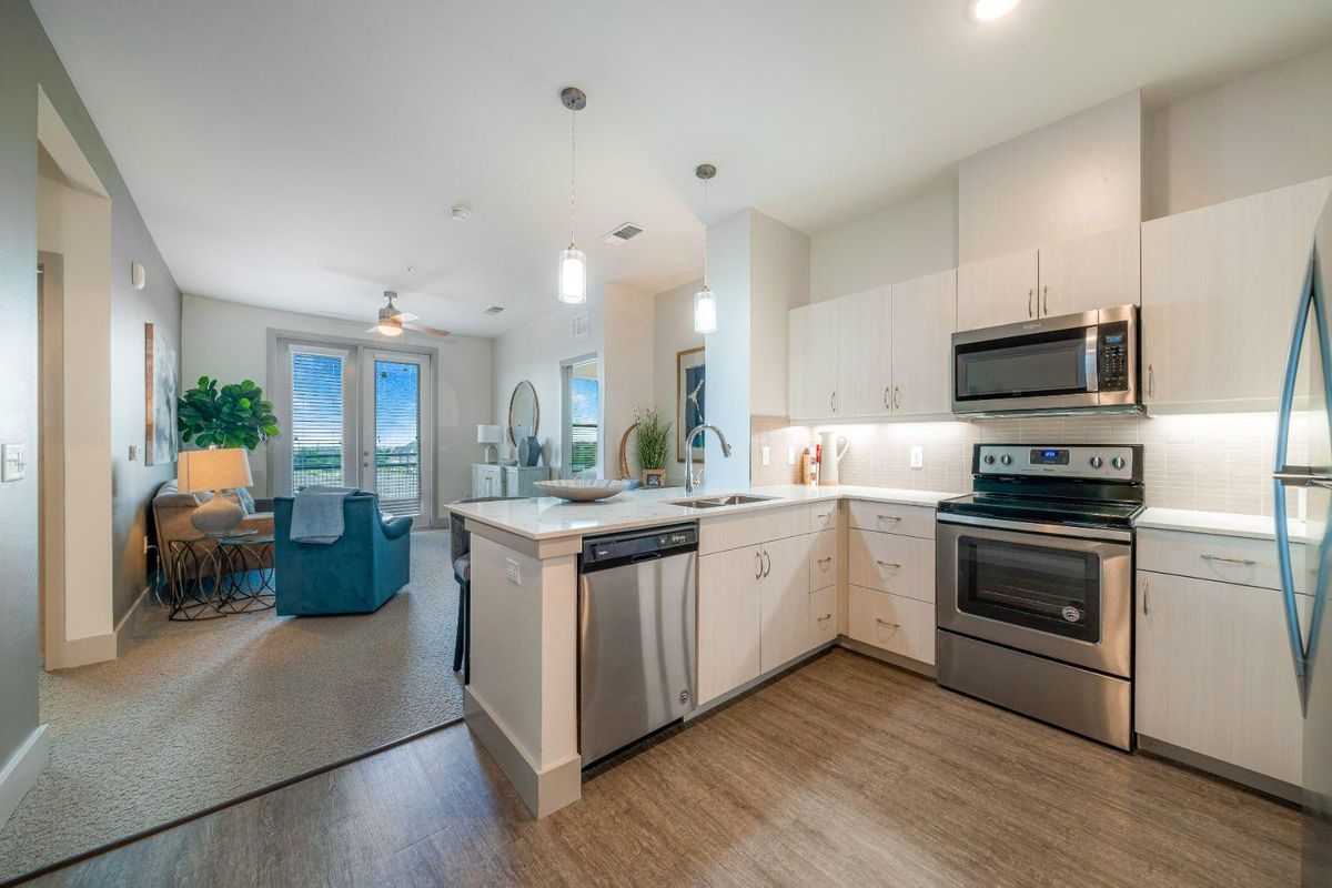 A modern kitchen with stainless steel appliances opens up to a bright, inviting living area.