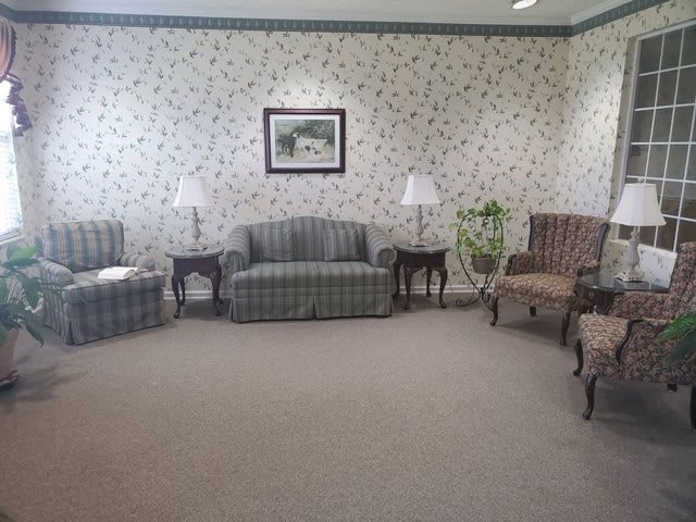 A classic waiting room with traditional furniture and floral wallpaper.