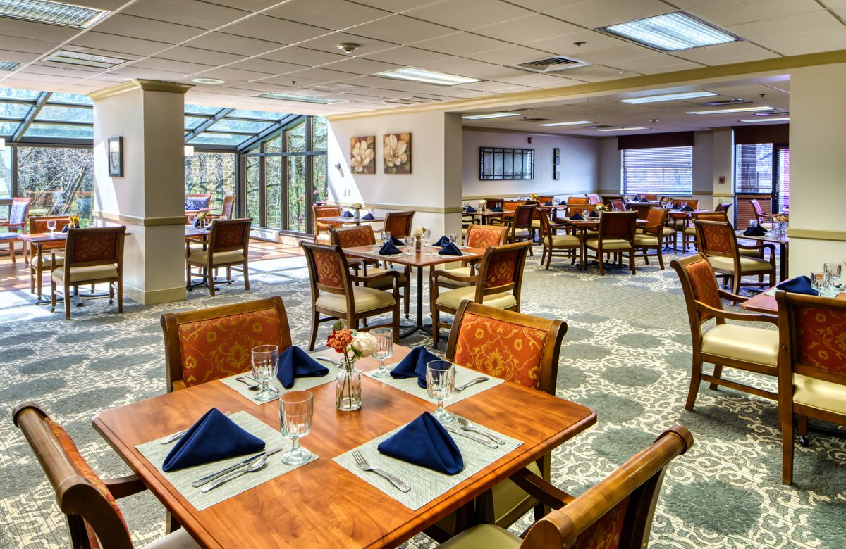 A well-appointed dining room with neatly arranged tables and chairs, featuring elegant table settings with navy blue napkins and cutlery.
