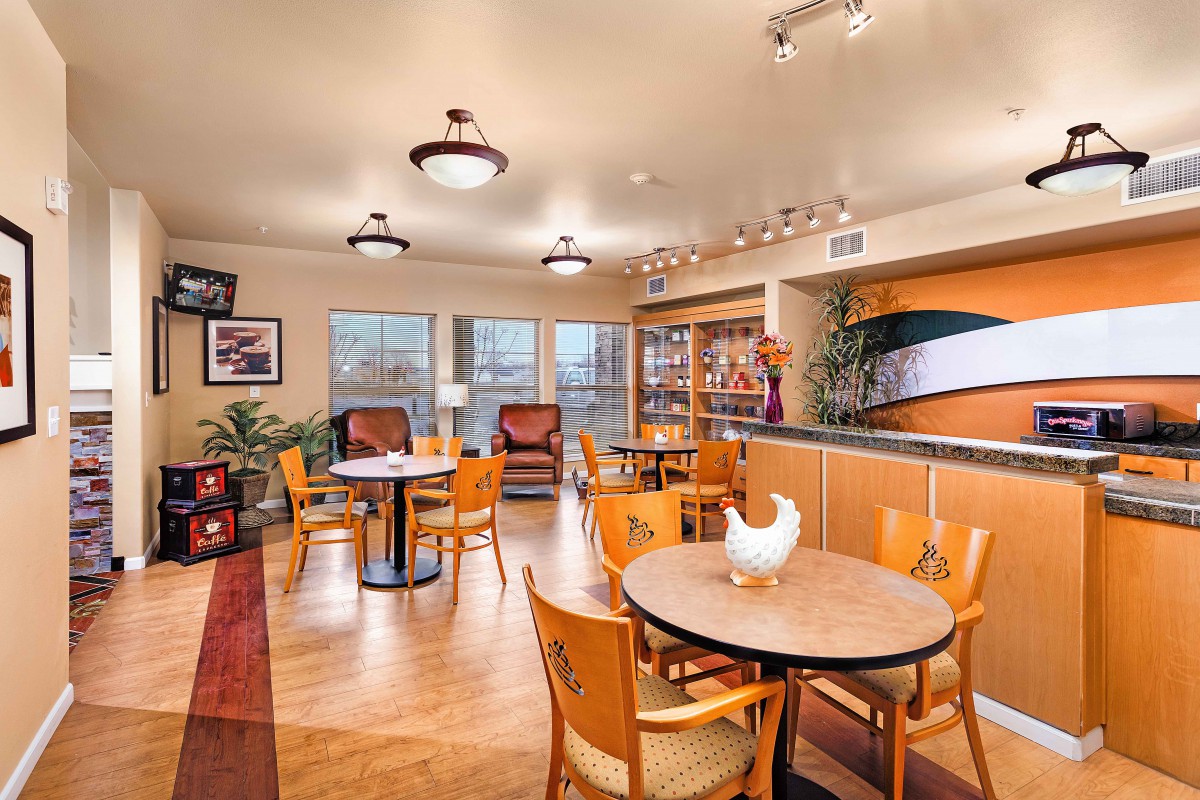 A cozy dining area with tables and chairs, decorated with warm lighting.