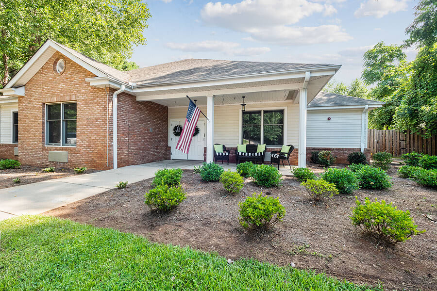 A cozy suburban house with a landscaped front yard and an inviting porch adorned with a flag.