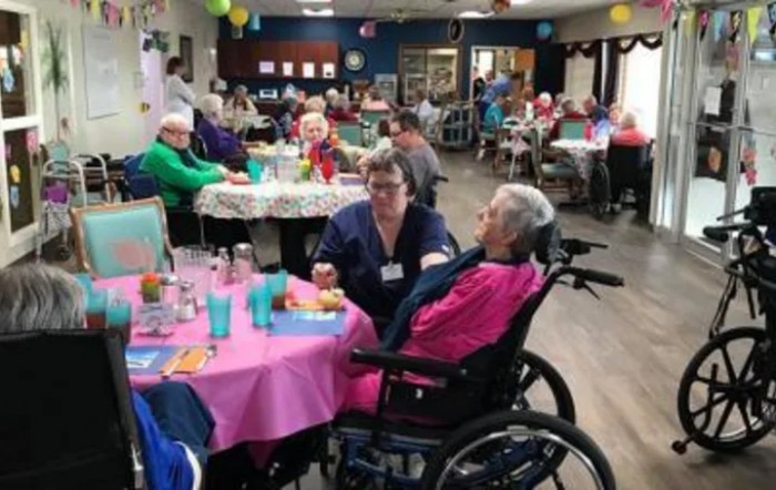 A caregiver interacting with residents at a nursing home during a communal gathering.