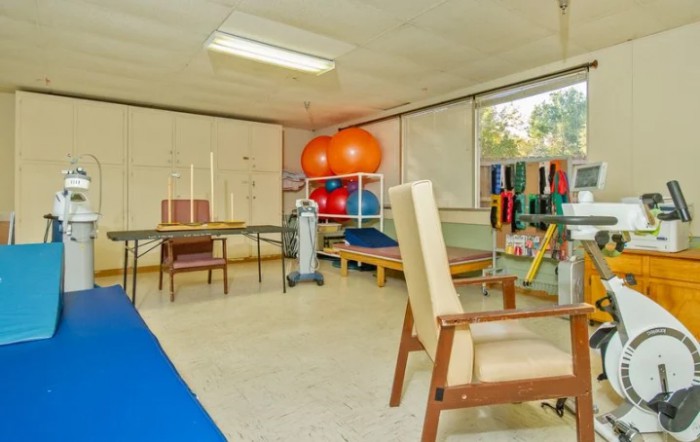 A rehabilitation room equipped with therapy balls, chairs, and tables for physical therapy exercises.