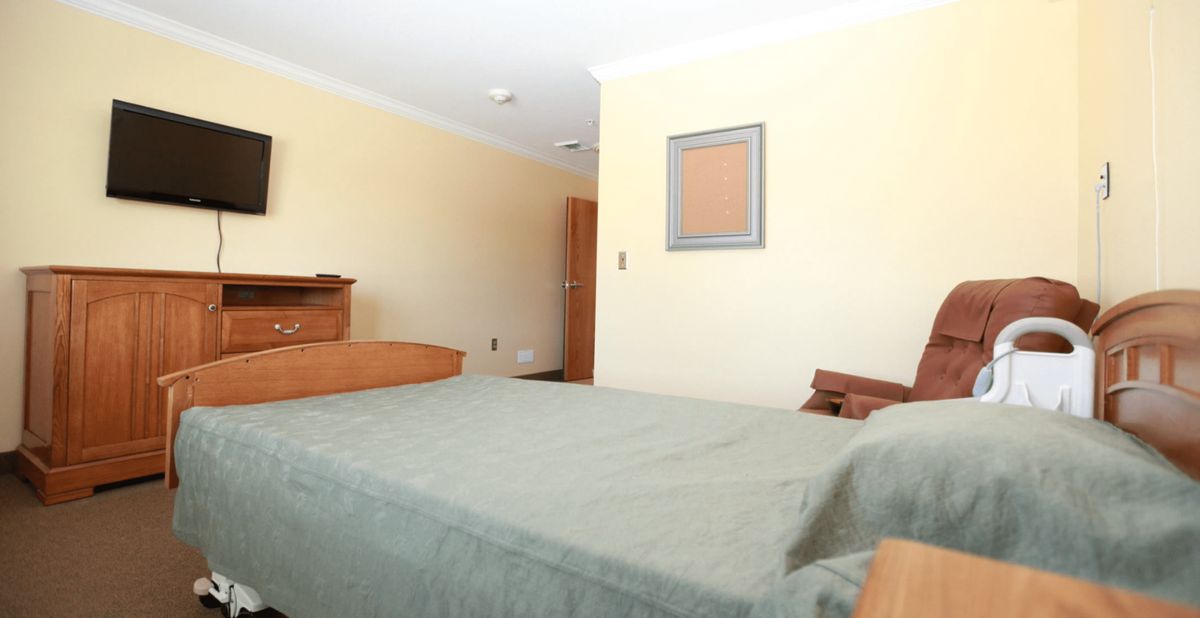 A simple and clean bedroom with a neatly made bed and wooden furniture.